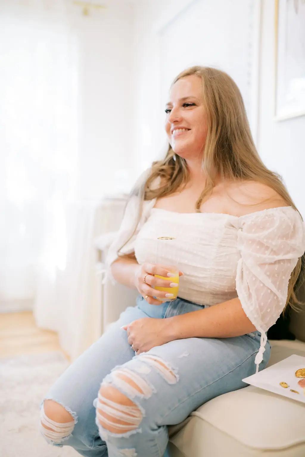 Bride sitting on a couch and holding a mimosa