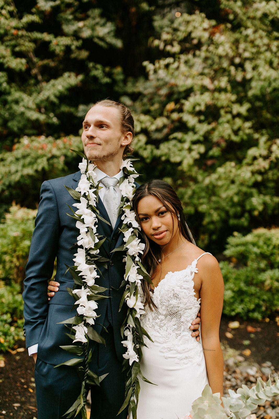 groom in blue suit with Hawaiian lei and bride wearing beaded crepe wedding dress from Charlotte's