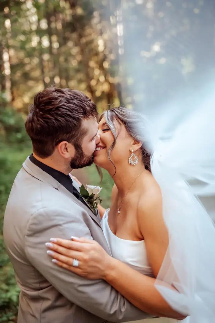Bride and groom kiss in forest