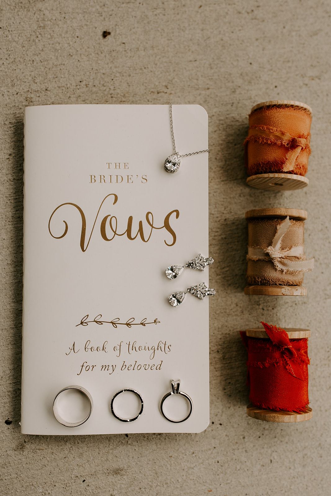 bride details with jewelry and vow book