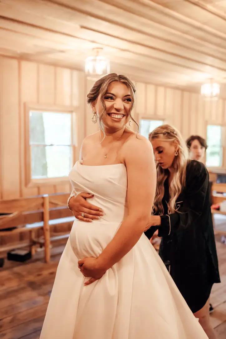Bride showing baby bump on wedding day