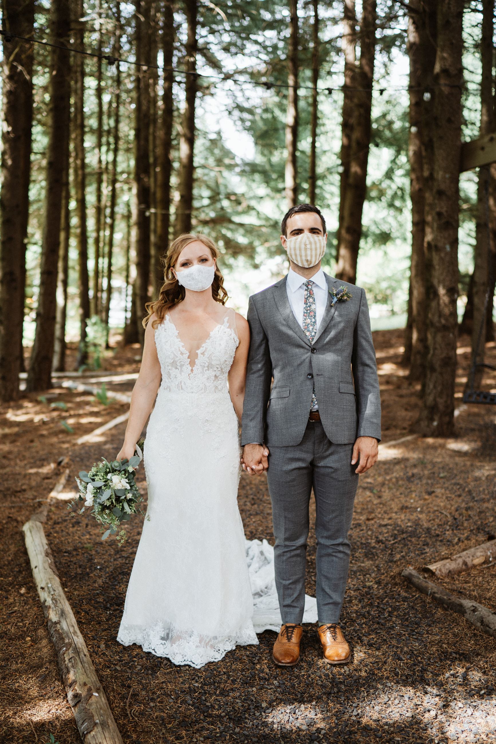 bride and groom holding hands in masks