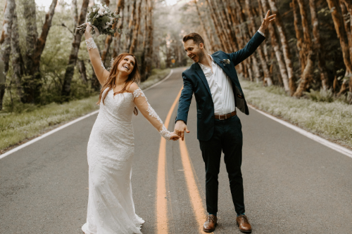 bride and groom holding hands on road