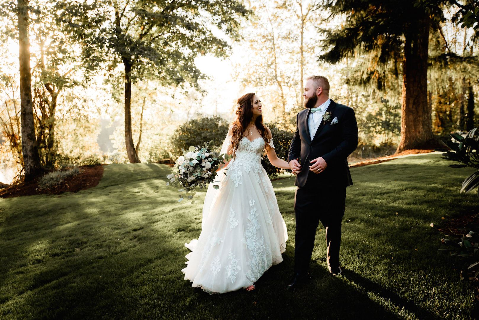 bride in Justin Alexander ball gown from Charlotte's Weddings in Portland, Oregon and walking holding hands with groom